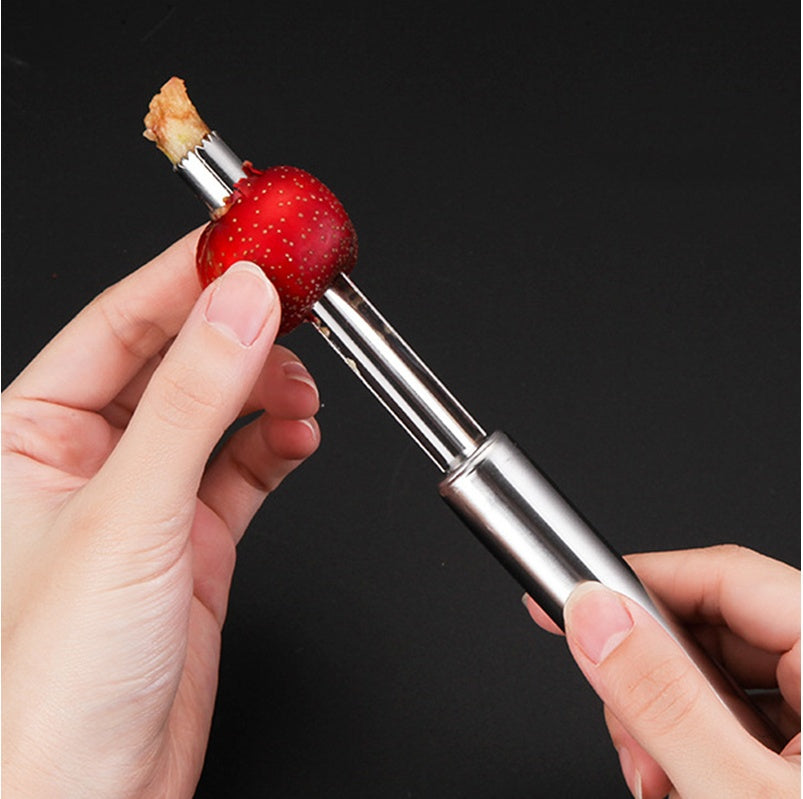 Strawberry being pierced with a metal tool against a black background