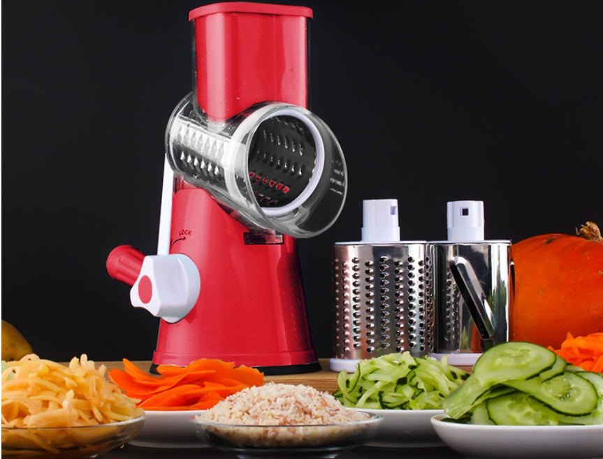 Red manual food grinder with sliced vegetables on a black background