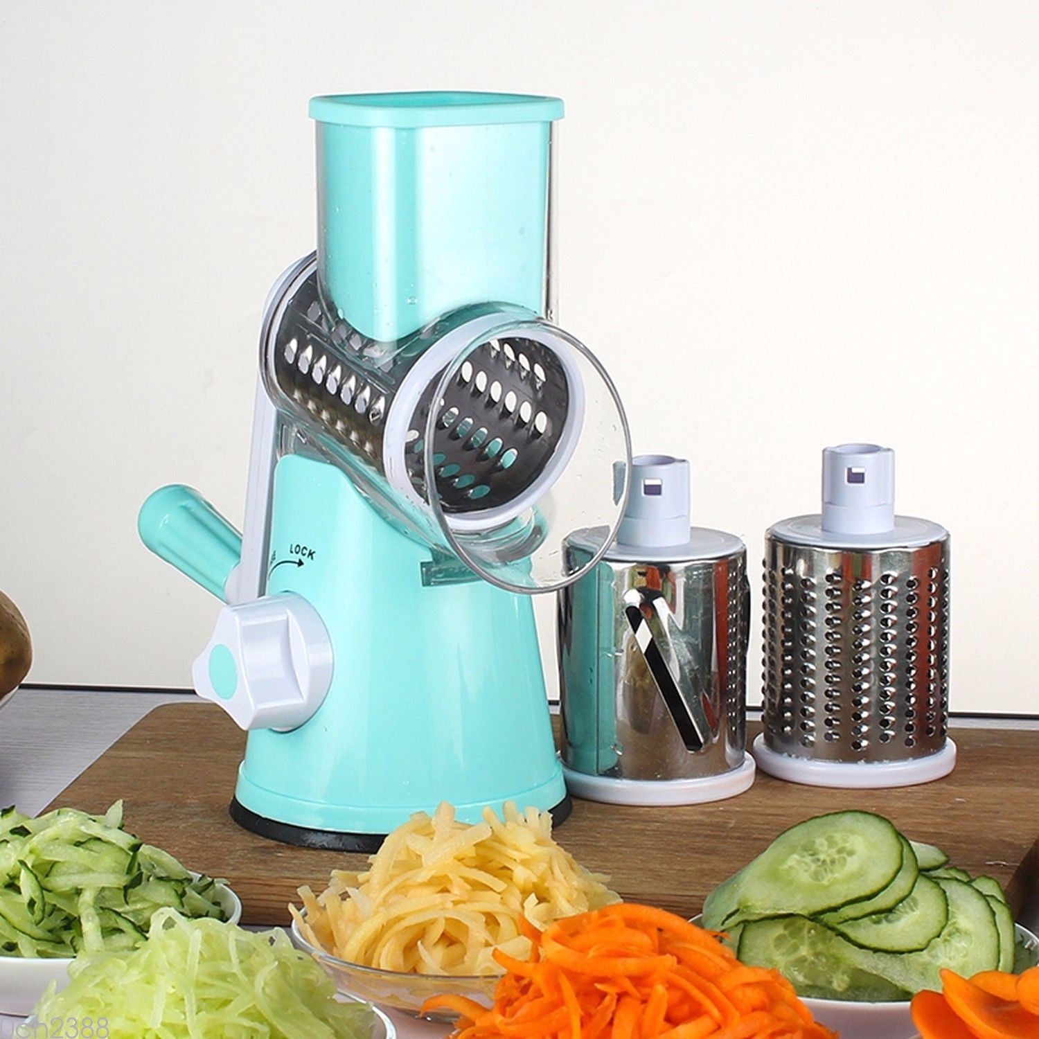 Turquoise manual vegetable spiralizer with variously sliced vegetables on a wooden surface.