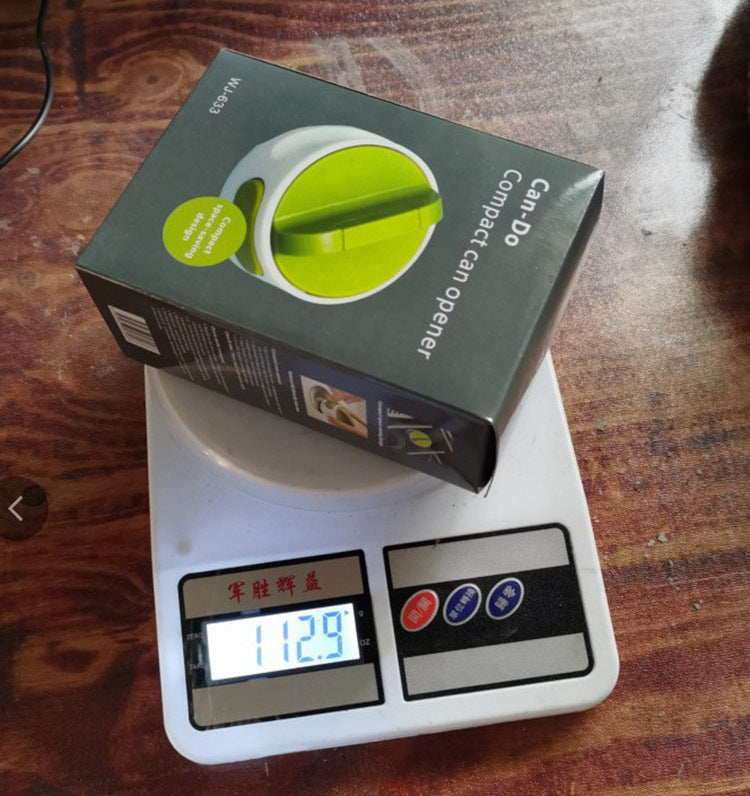 Box of a compact can opener on a digital scale with a wooden surface background