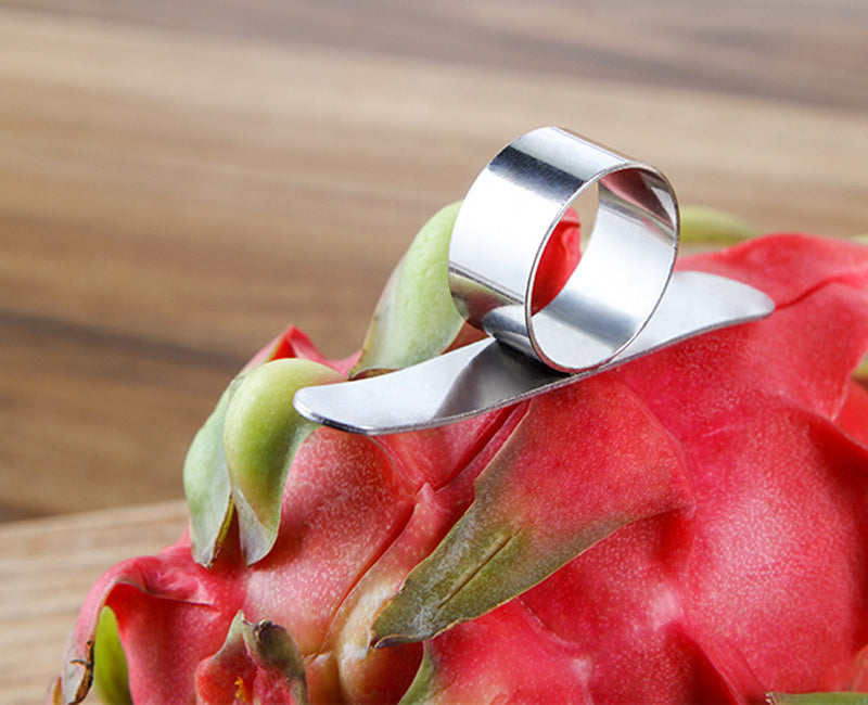Metallic fruit peeler on a dragon fruit with a wooden background