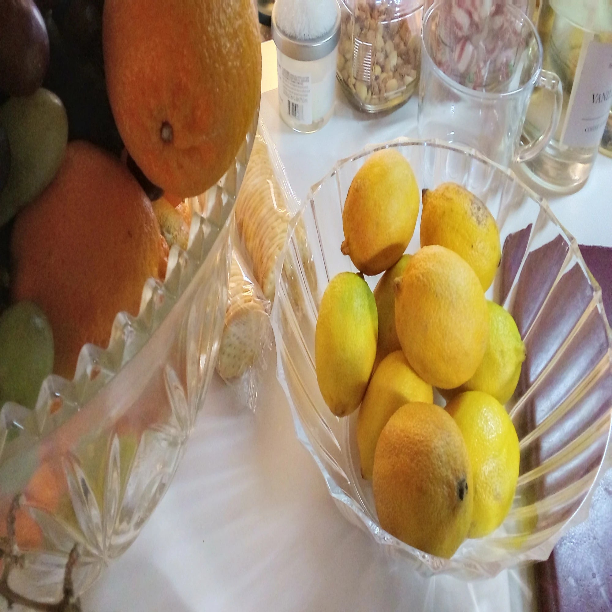 Bowl of lemons on a table with other fruits and items in the background